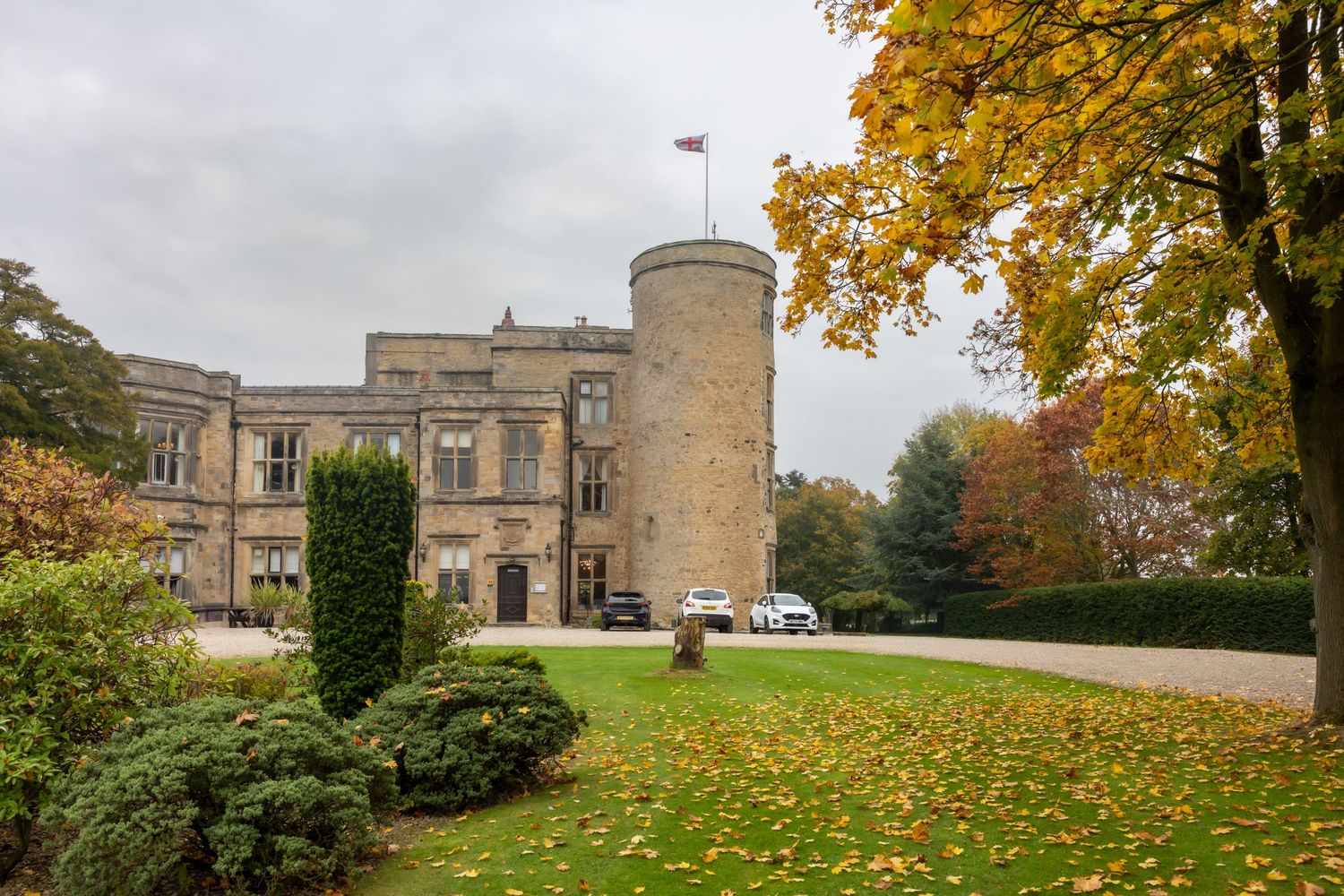 A panoramic view of a historic stone castle with autumn trees and landscaped grounds on an overcast day. Walworth Castle wedding darlington