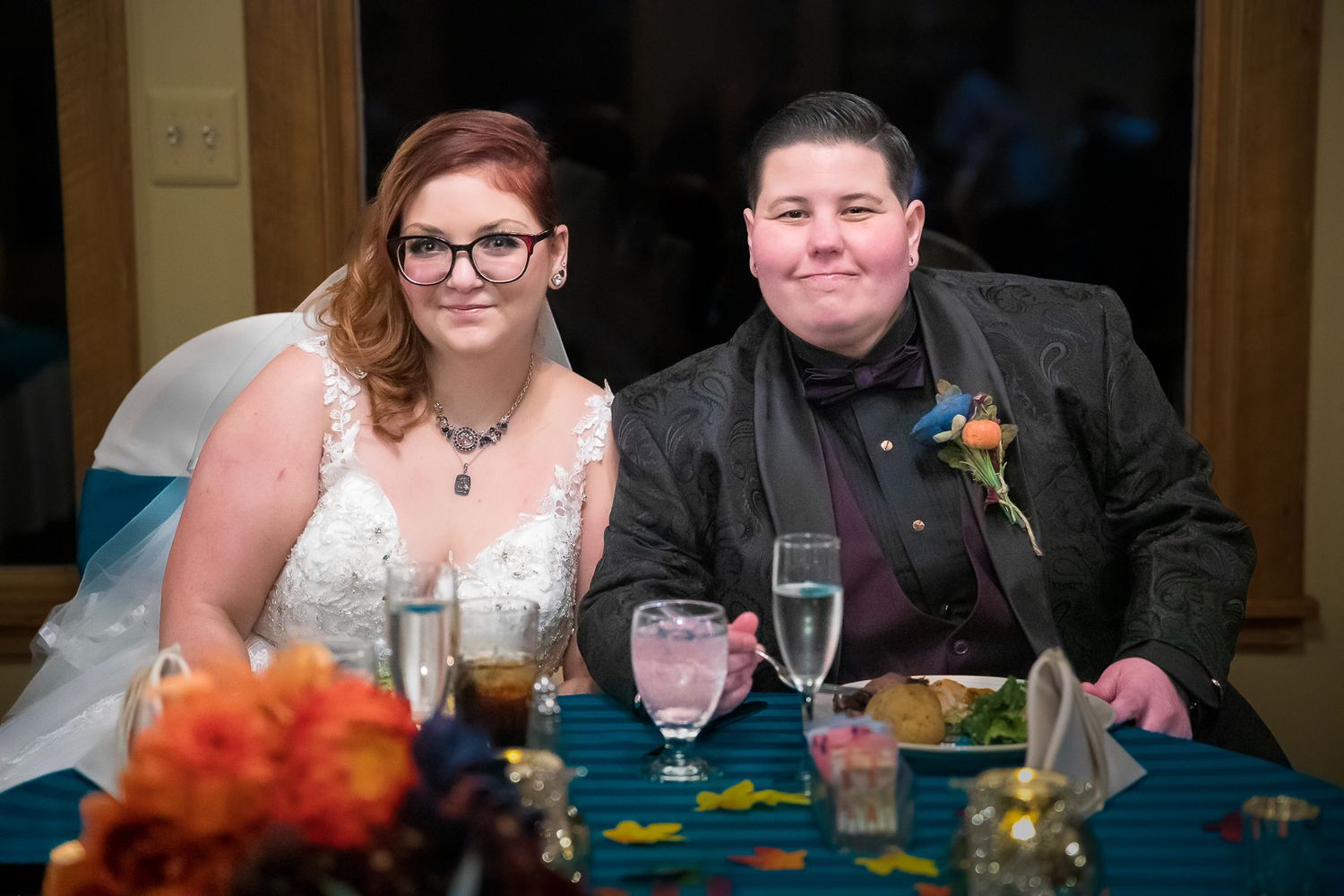 People seated at a formal dining table with blue tablecloths and glassware during a celebration event.