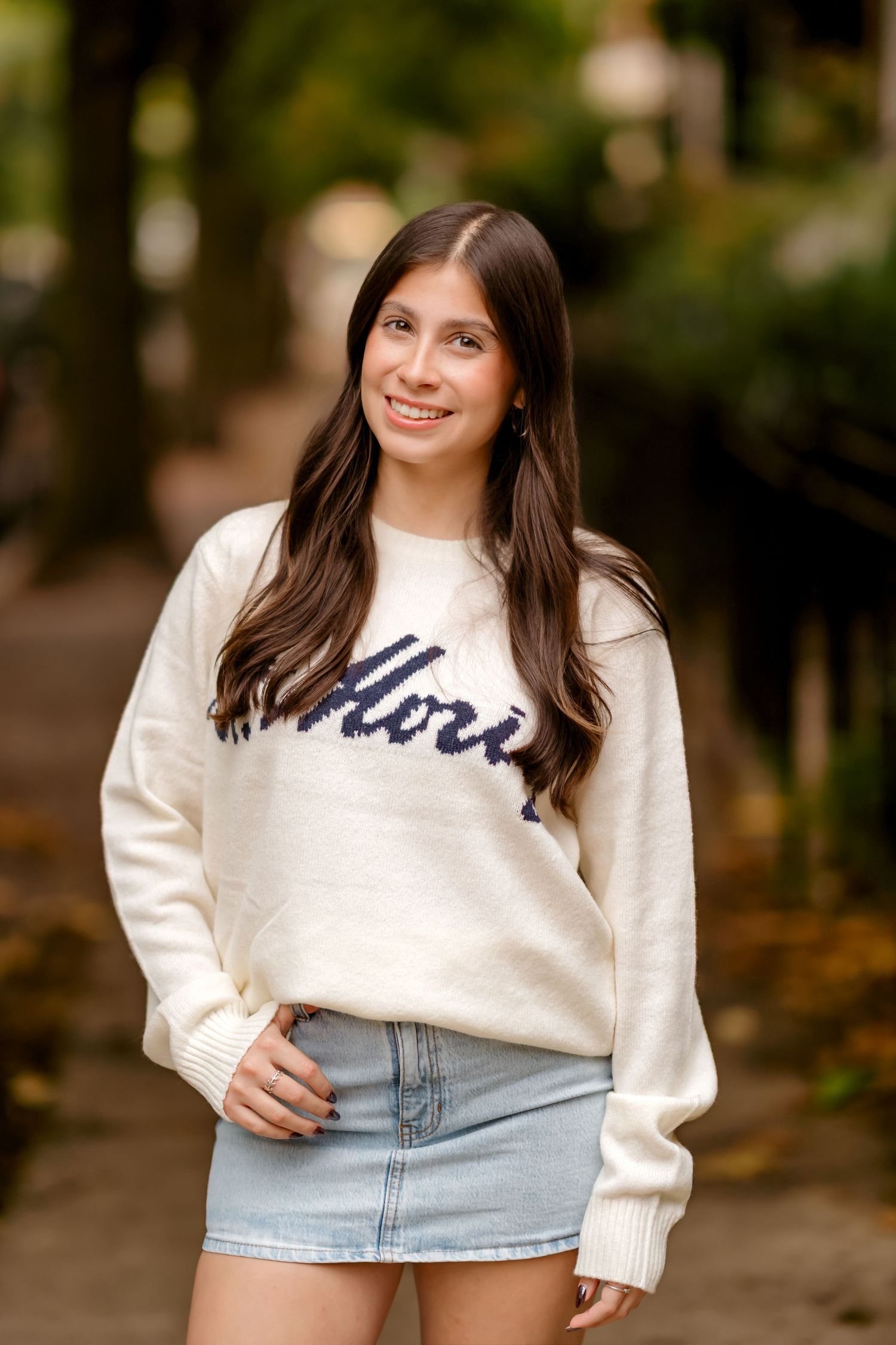 A series of five fashion photos showing a person in a cream colored sweater and light denim skirt in an outdoor setting.