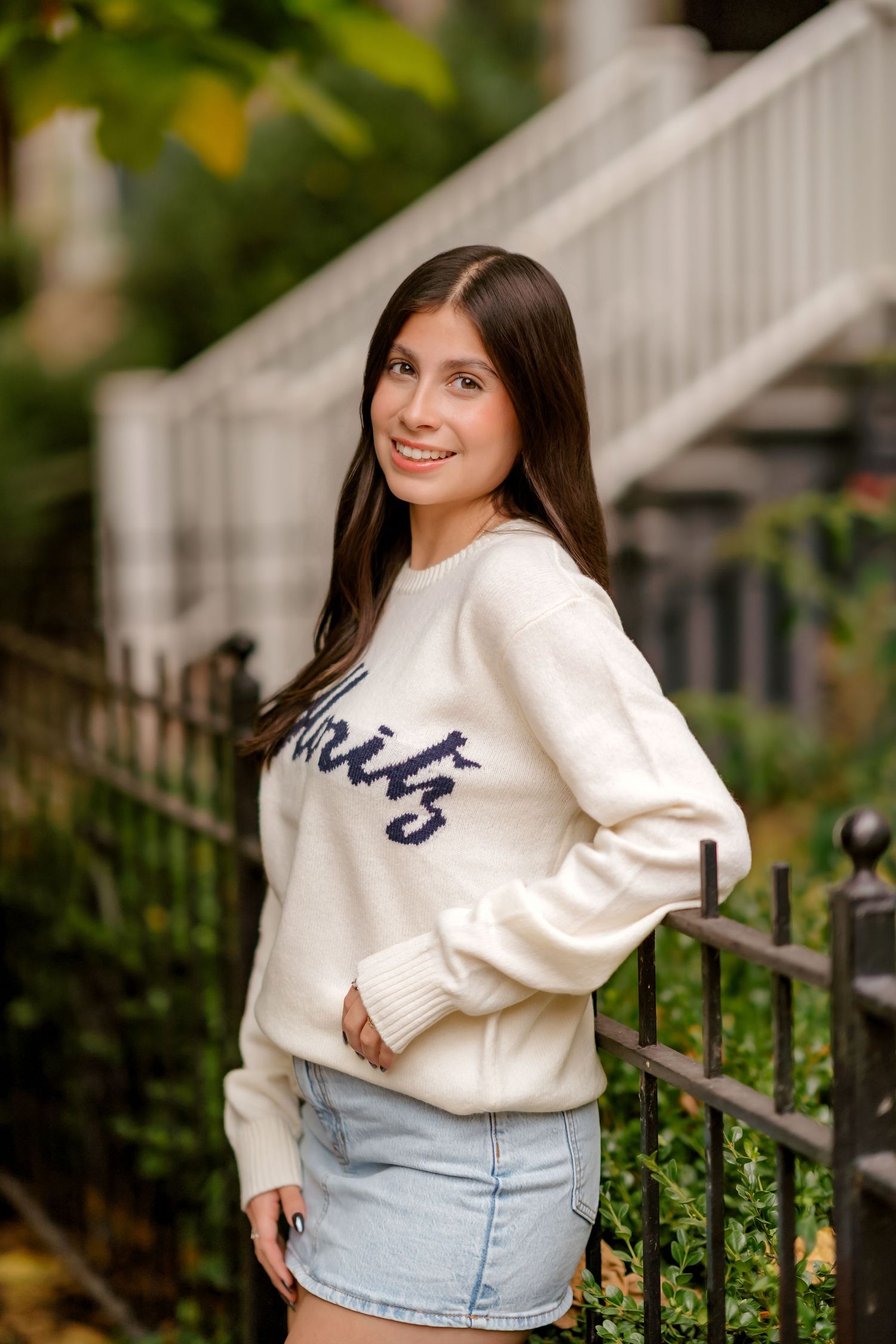 Fashion photo series showing casual outfit with cream sweatshirt and denim skirt against white railing.