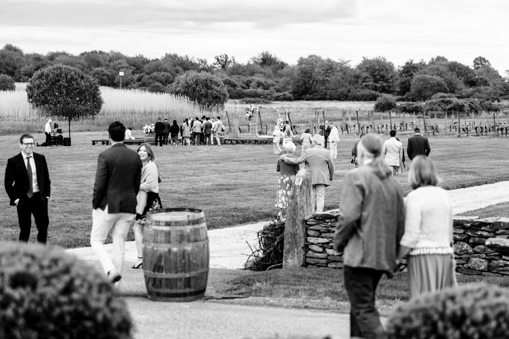 Panoramic view of an outdoor wedding ceremony setup in a rustic field with scattered seating arrangements.
