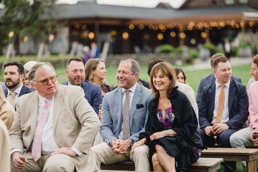 Wedding guests seated at outdoor tables with string lights creating a warm ambiance.