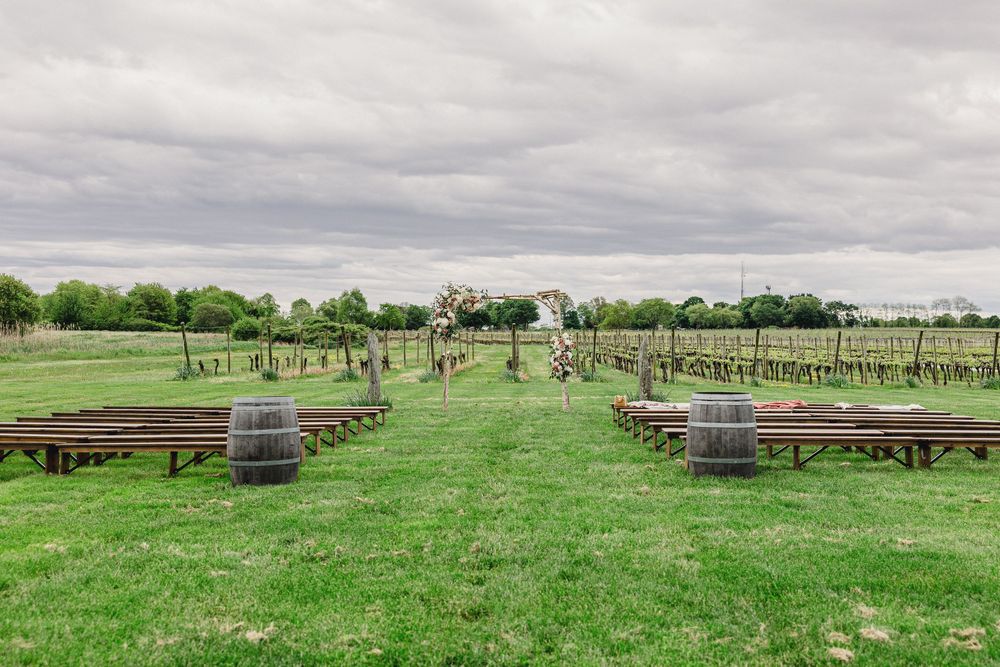 Panoramic view of a grassy field with wooden benches set up for an outdoor wedding ceremony.