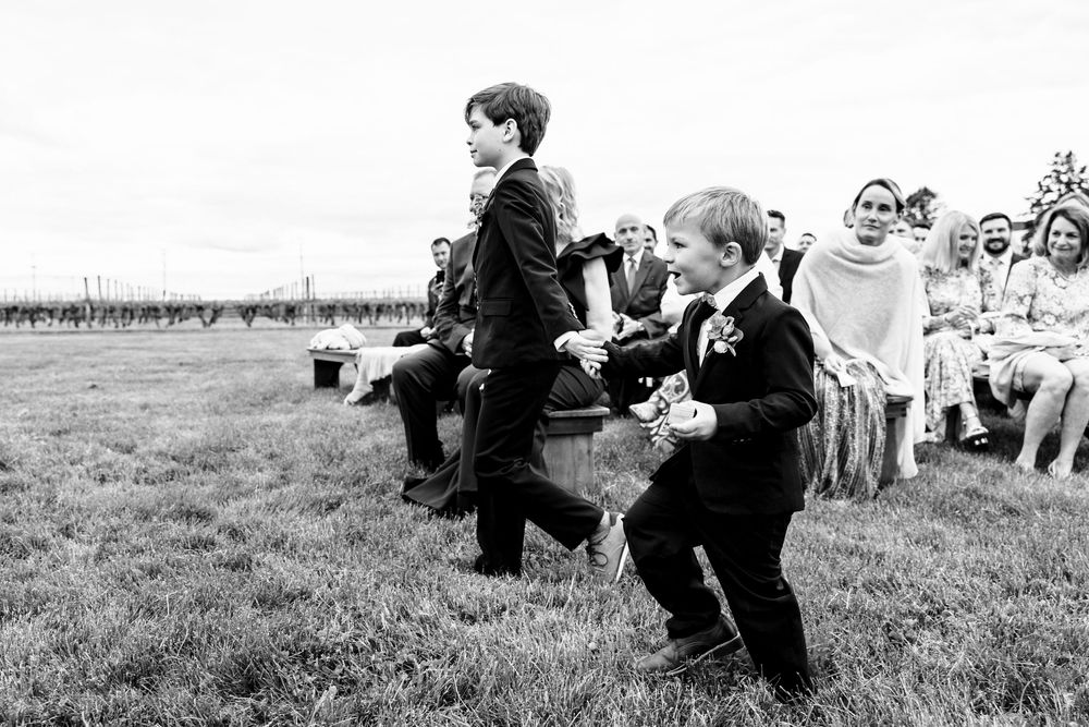 A black and white photo of young children running and playing during an outdoor wedding celebration.