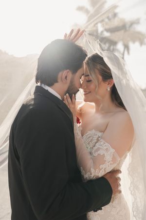 Dreamy wedding portraits captured in soft light with flowing veil creating romantic atmosphere.
