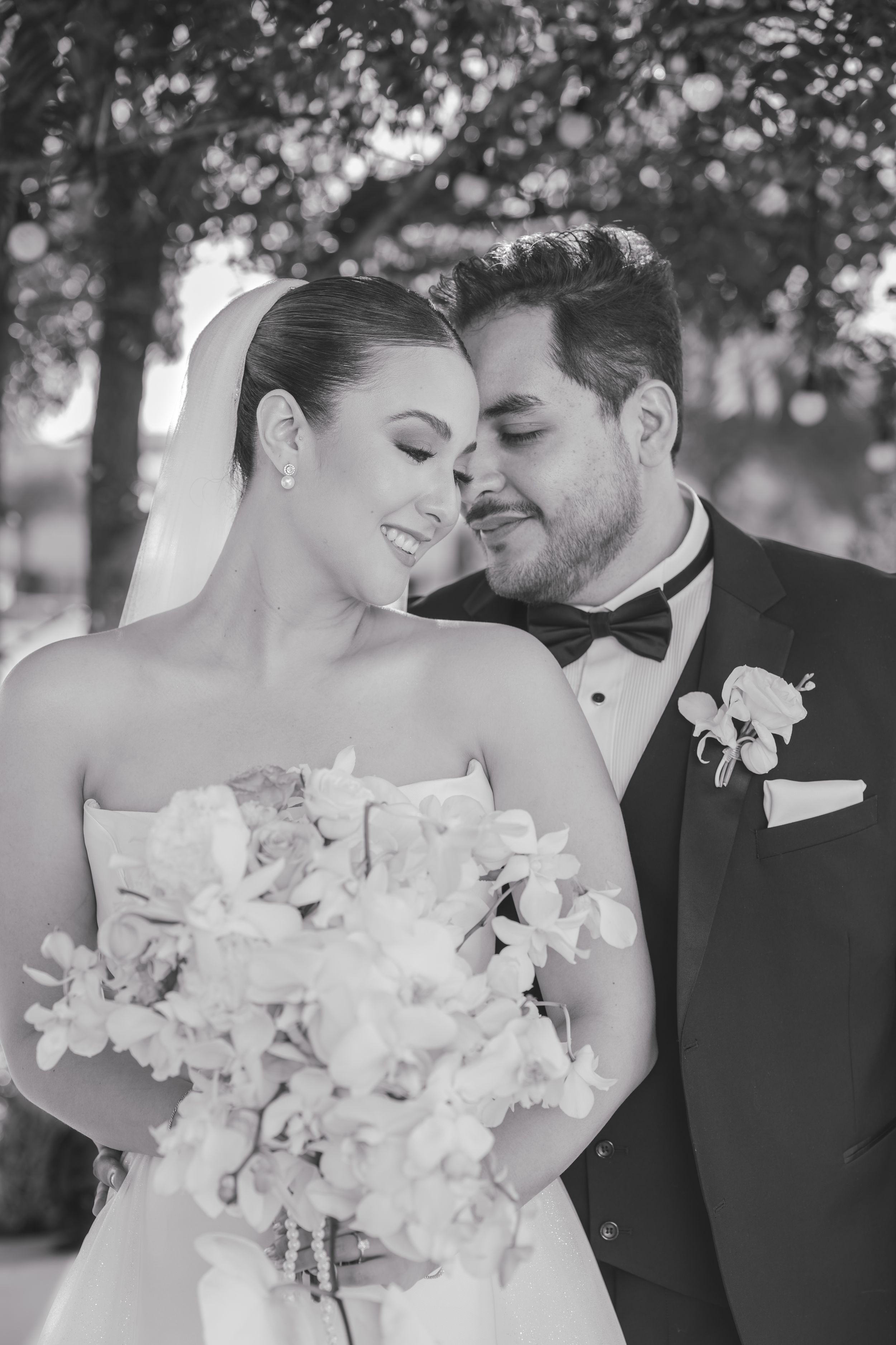 A romantic wedding portrait of a couple embracing with the bride holding a white floral bouquet.