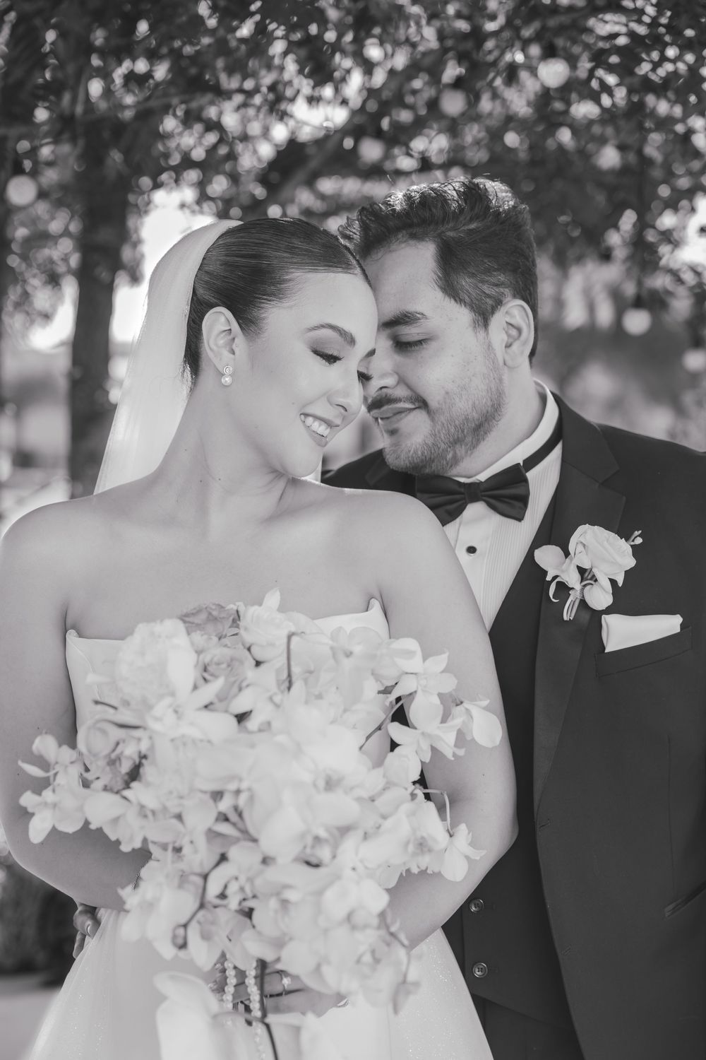 A romantic wedding portrait of a couple embracing with the bride holding a white floral bouquet.