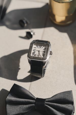 Elegant black bow tie and luxury watch arrangement for formal wedding attire.