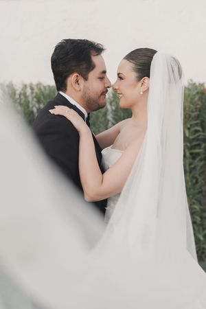 An intimate wedding portrait of a couple sharing a tender moment outdoors.