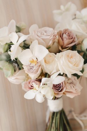 Delicate bridal bouquet featuring white orchids and blush roses in romantic composition.