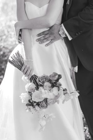 A black and white wedding photo showing a bouquet and formal attire details.