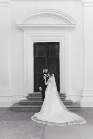 A classic black and white wedding portrait in front of an elegant doorway.