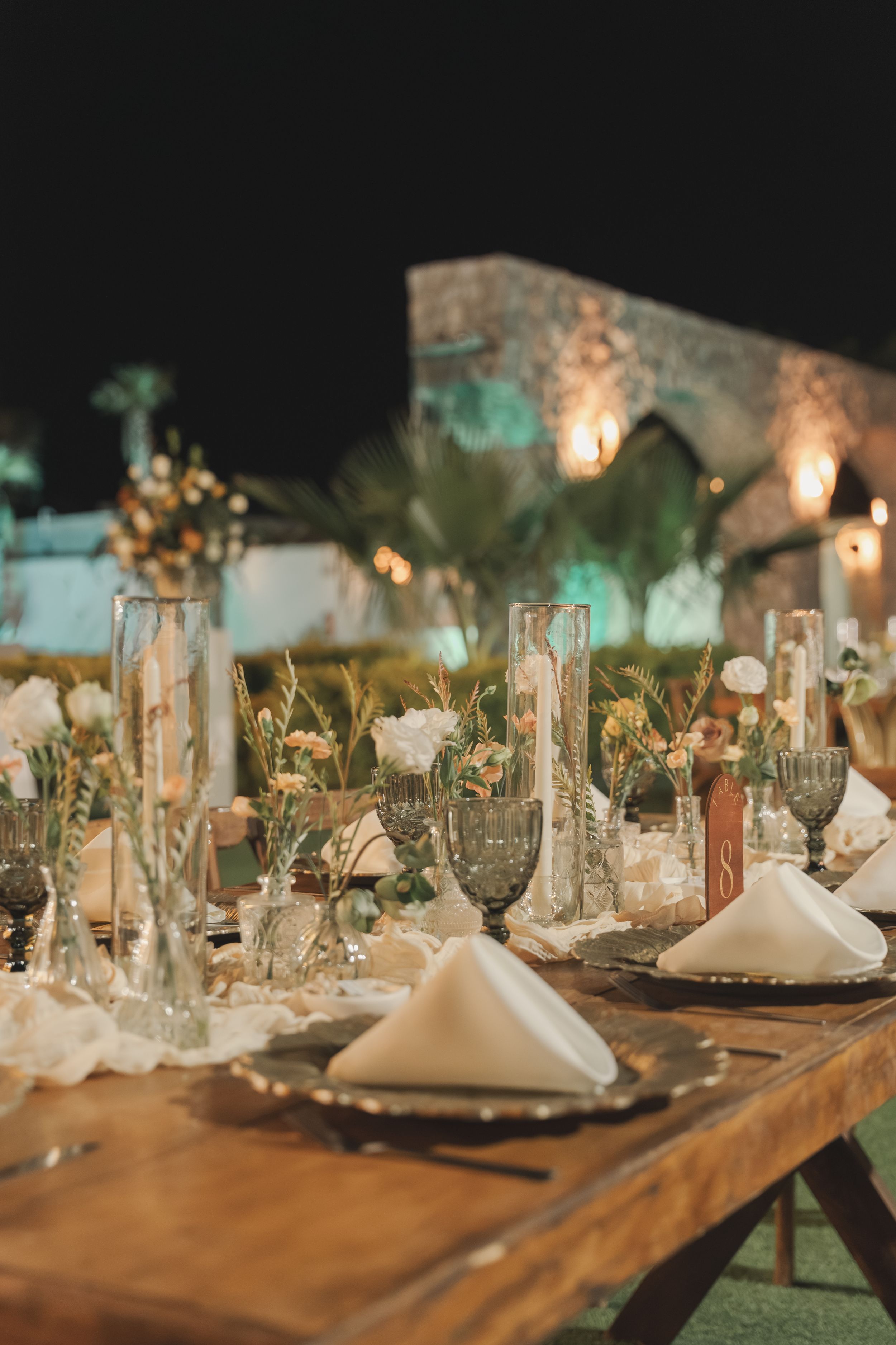 An elegant wedding reception table setting with candles and place settings at dusk.