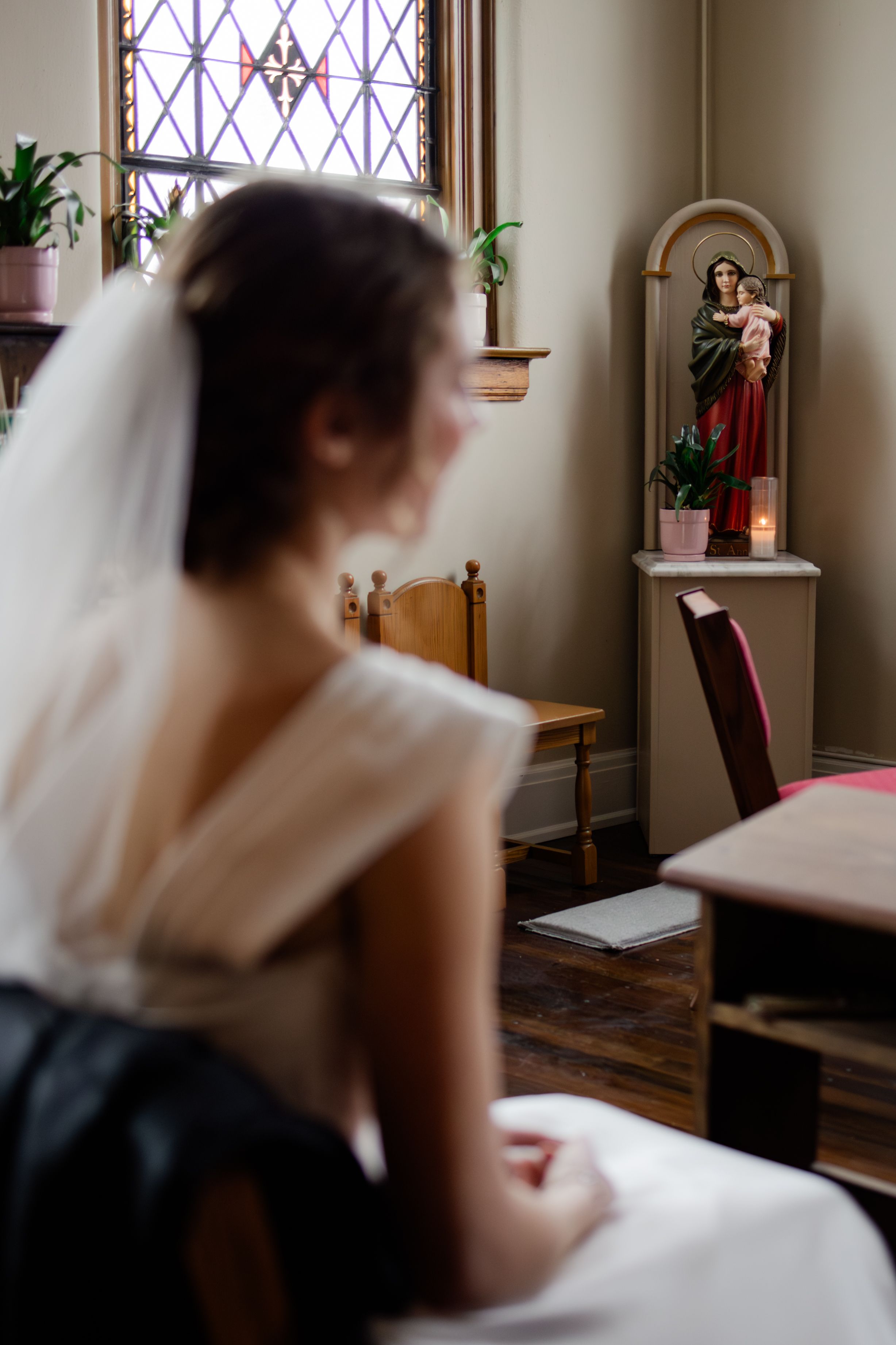 A delicate gold wedding ring rests on soft white lace fabric with intricate embroidered details.