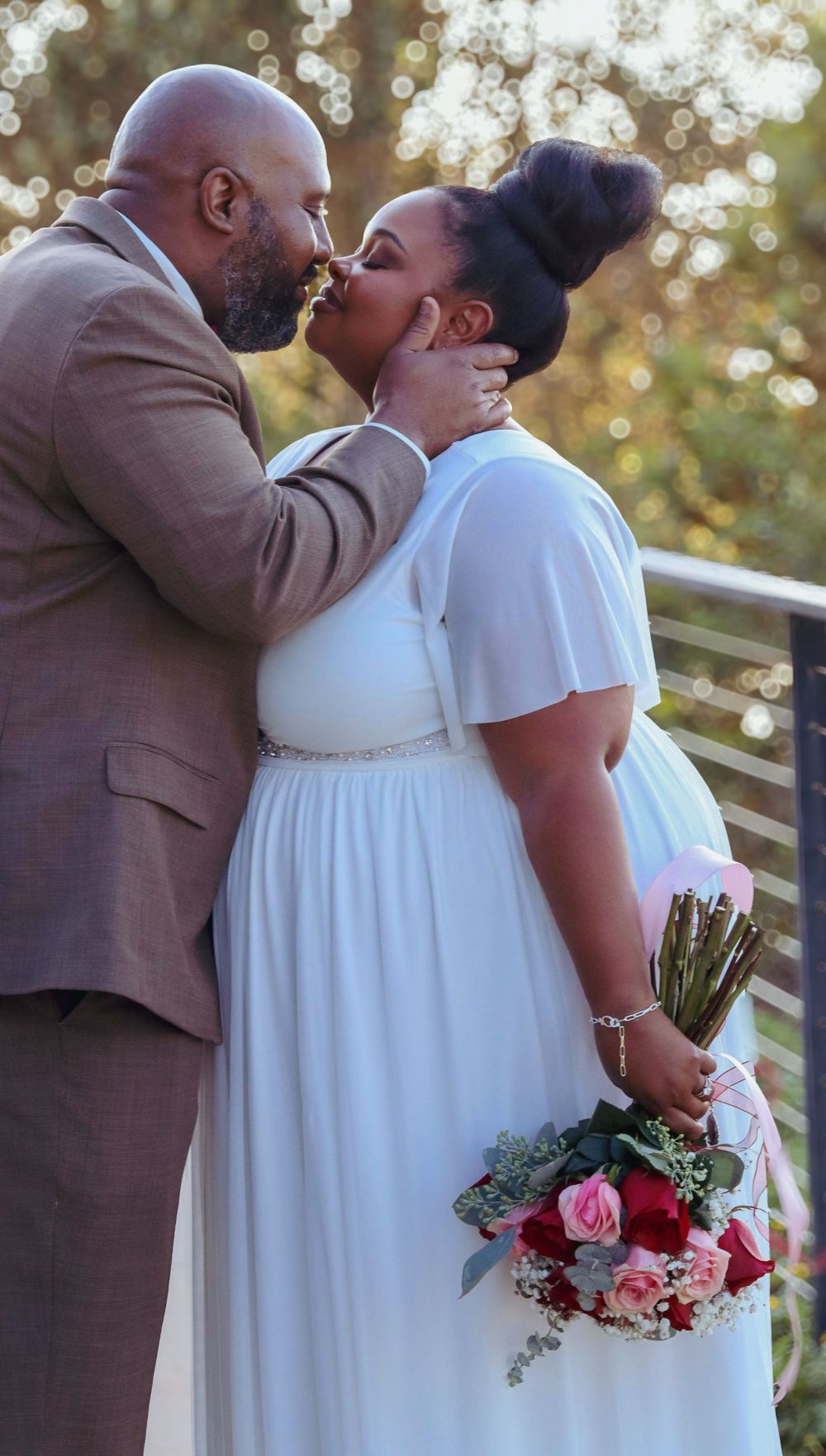 A tender moment between newlyweds with bokeh lighting and a pink floral bouquet.