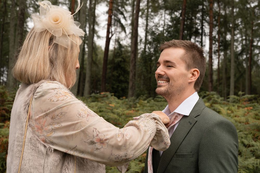 Couple sharing a joyful moment in a forest setting during their wedding photoshoot.