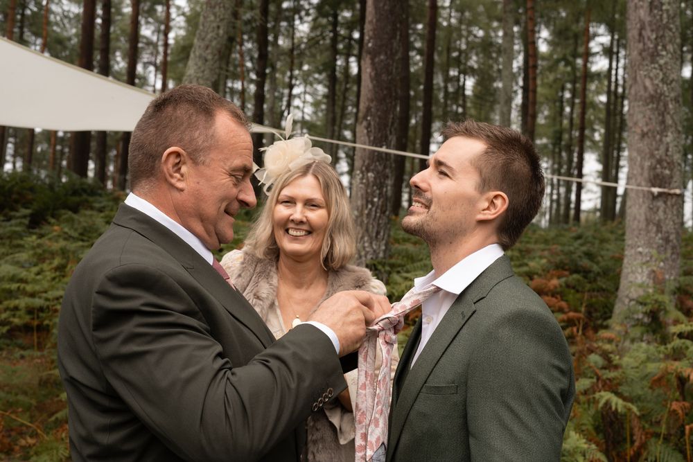 Wedding celebration in a forest setting with people sharing joyful moments and embraces.