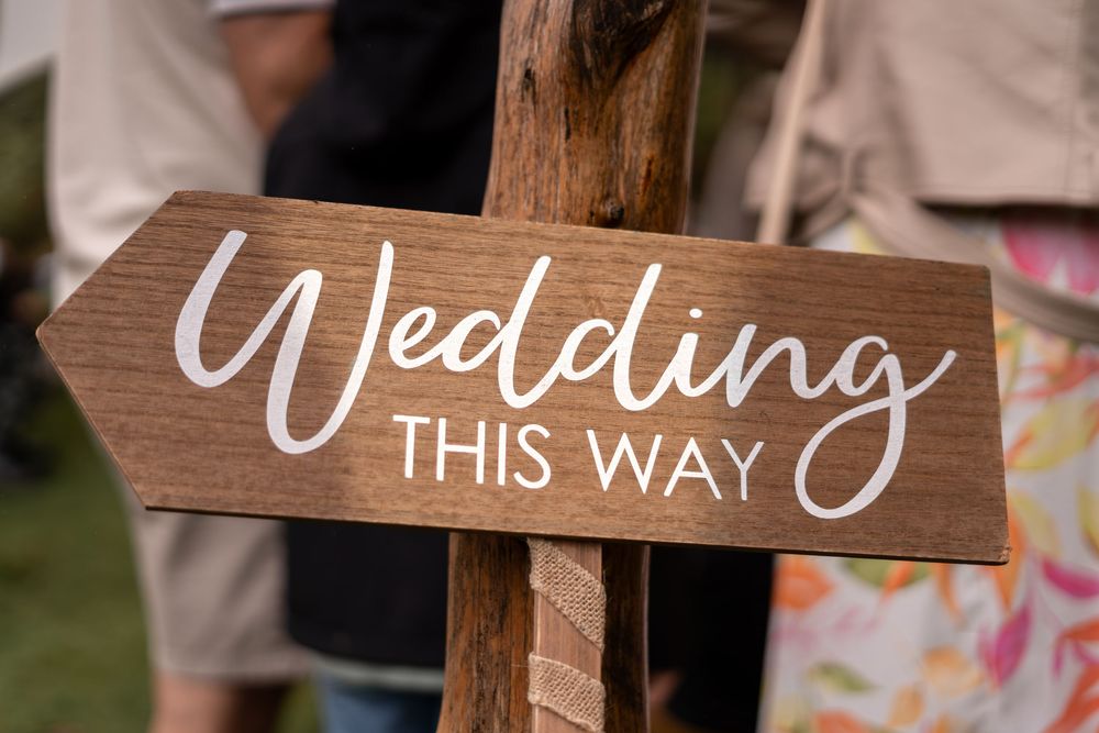 Rustic wooden wedding directional signs with elegant calligraphy displayed in an outdoor setting.