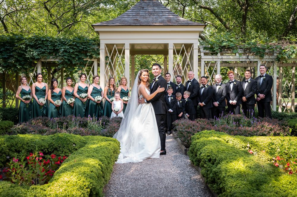 A wedding ceremony takes place in a lush garden setting with a white gazebo and manicured hedges at the 18th Century Garden in Philadelphia