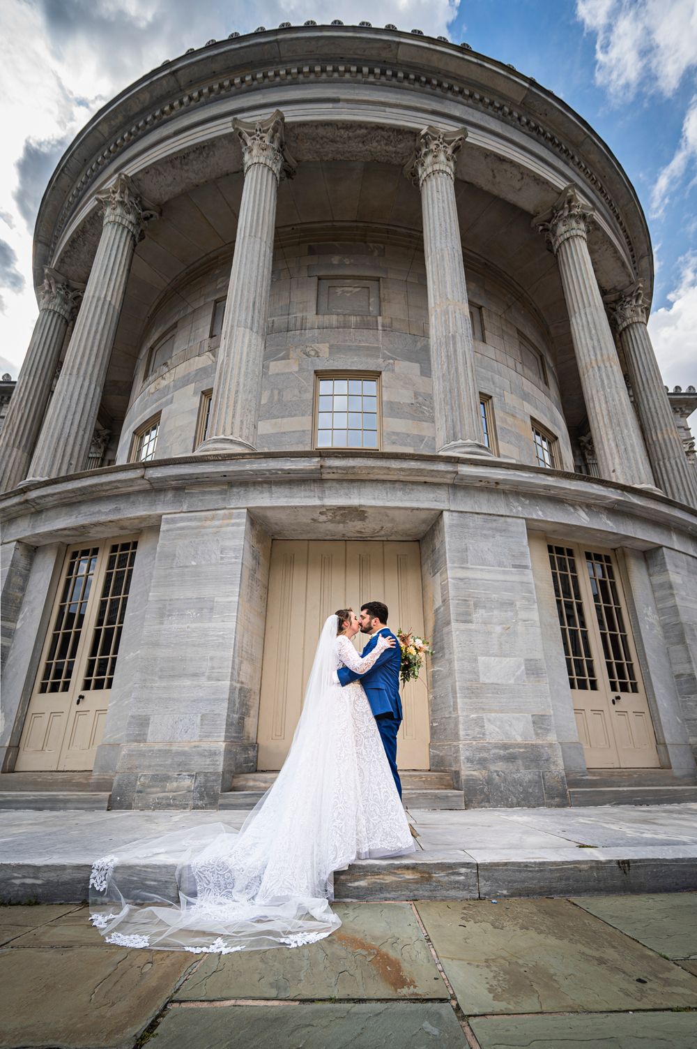 A wedding couple shares an intimate moment under the grand columns of the Merchants Exchange Building in Philly.