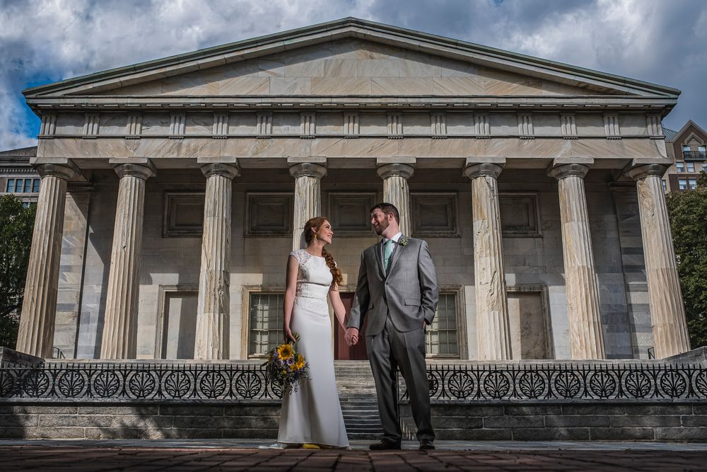 Elegant wedding couple poses between classical Greek columns at the 2nd Bank Building in Philadelphia.