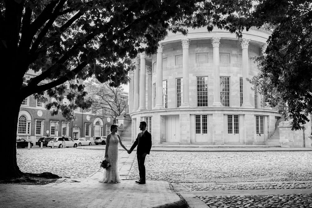 A black and white panoramic view of historic colonial buildings with trees and pathways at a university campus.