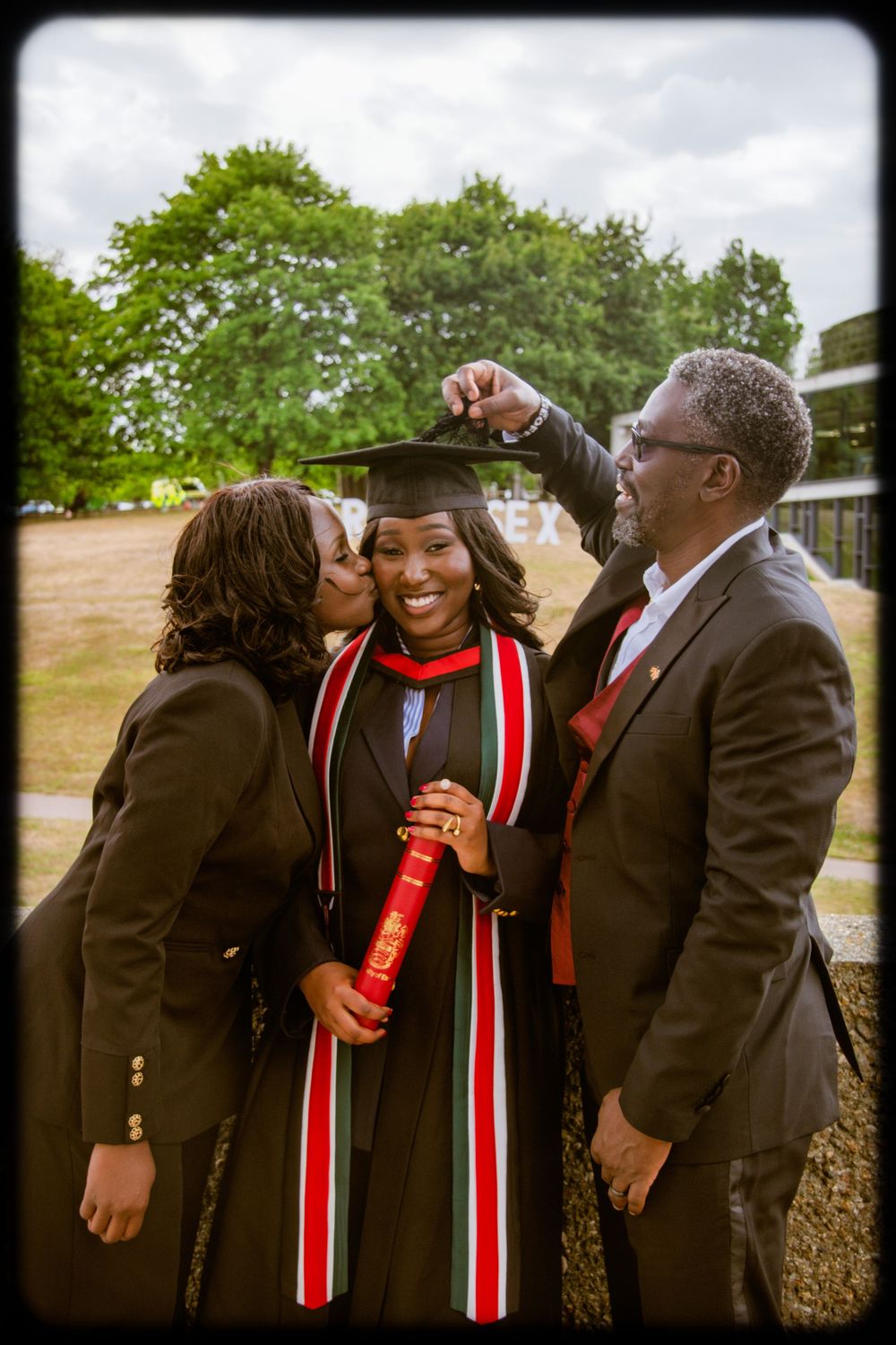 A graduation celebration scene with family members sharing joyful moments outdoors in formal attire.