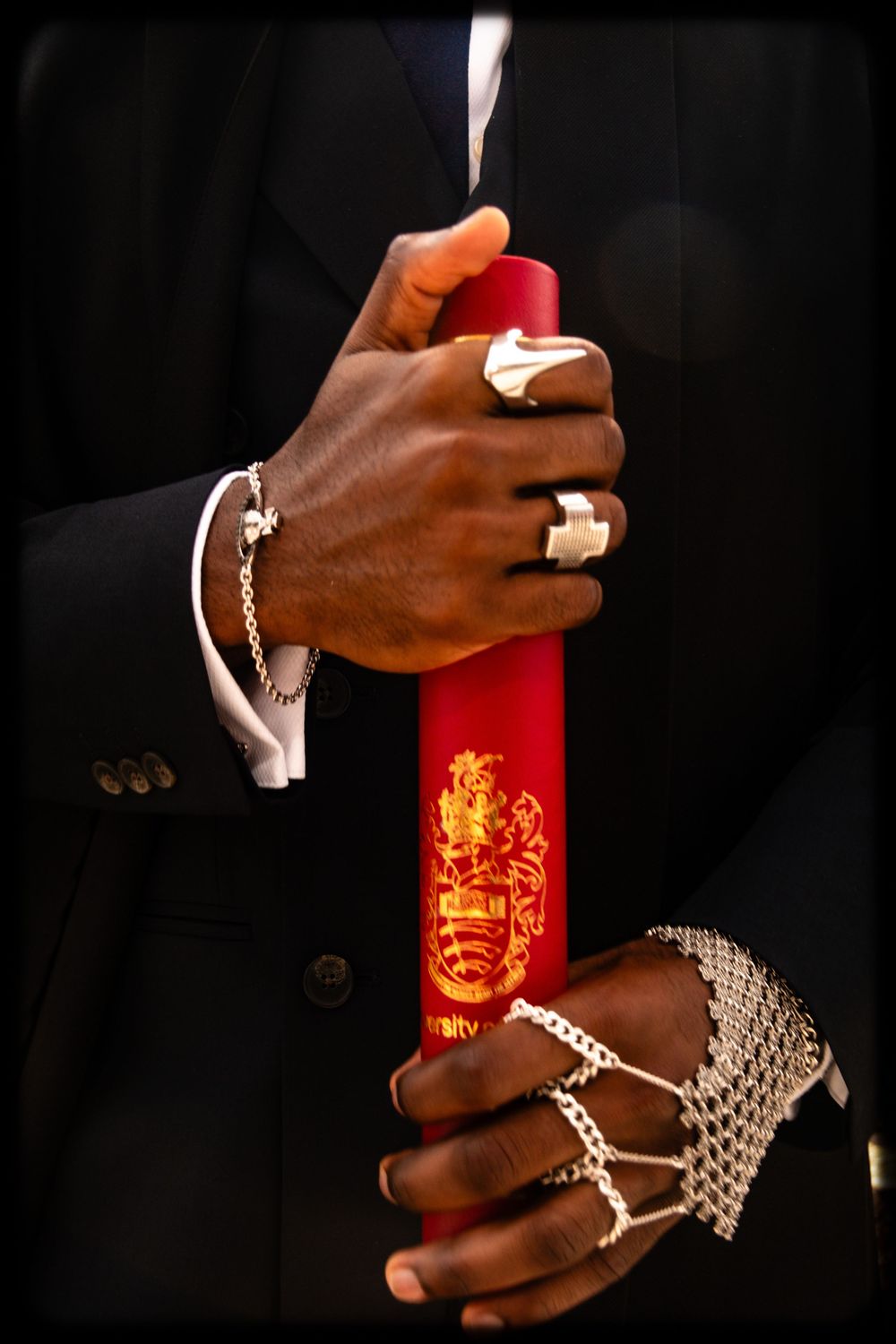 Hands holding a glowing red bottle with ornate designs against a dark background.