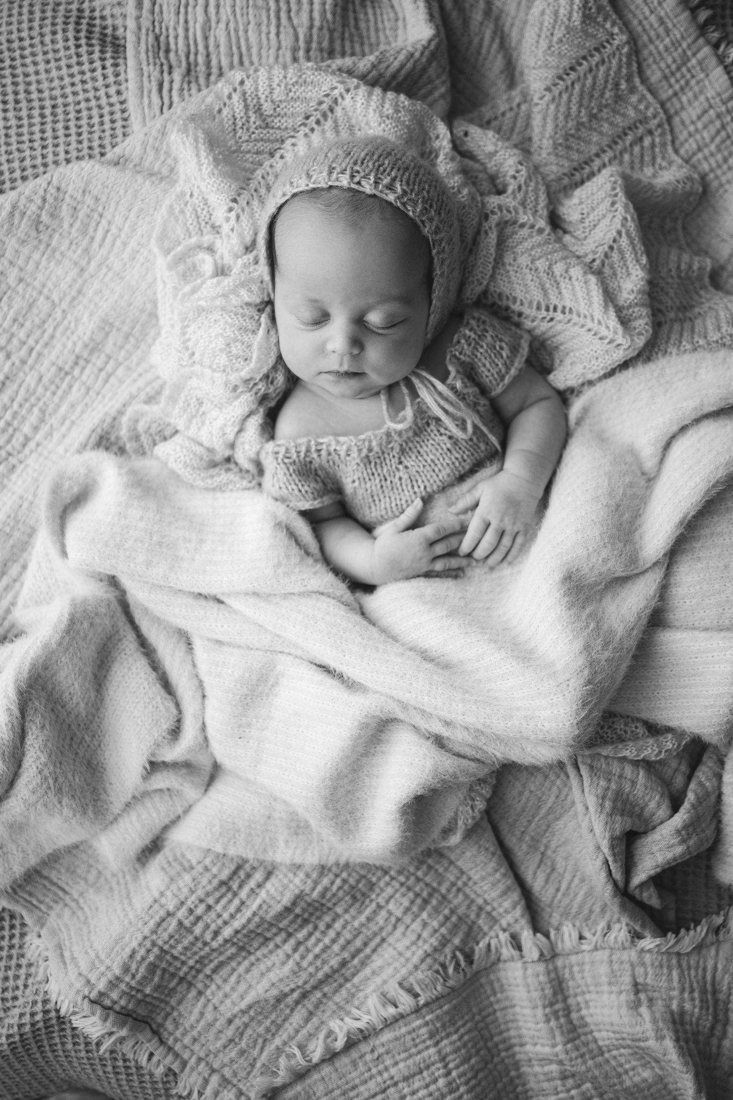During an in-home session, a newborn baby girl sleeps with her hands folded as a photographer based in Portland, Dorset takes her picture.