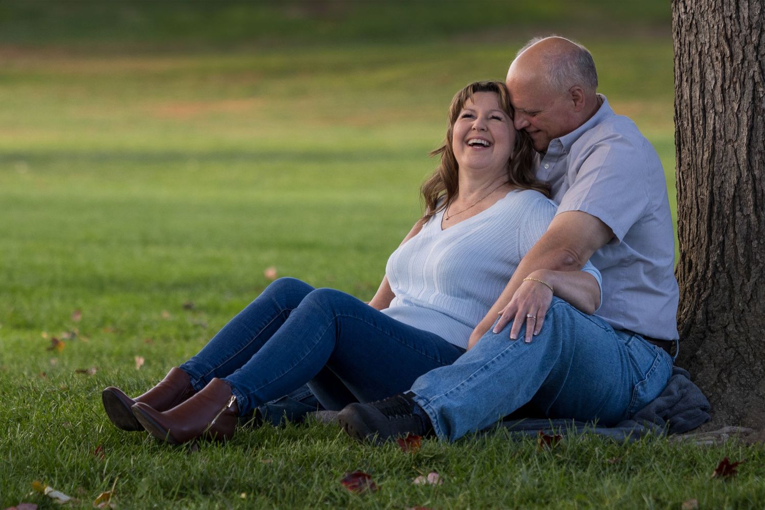 Frederick Maryland Wedding Photographer    A couple lounges together on grass under trees during an outdoor photo session.