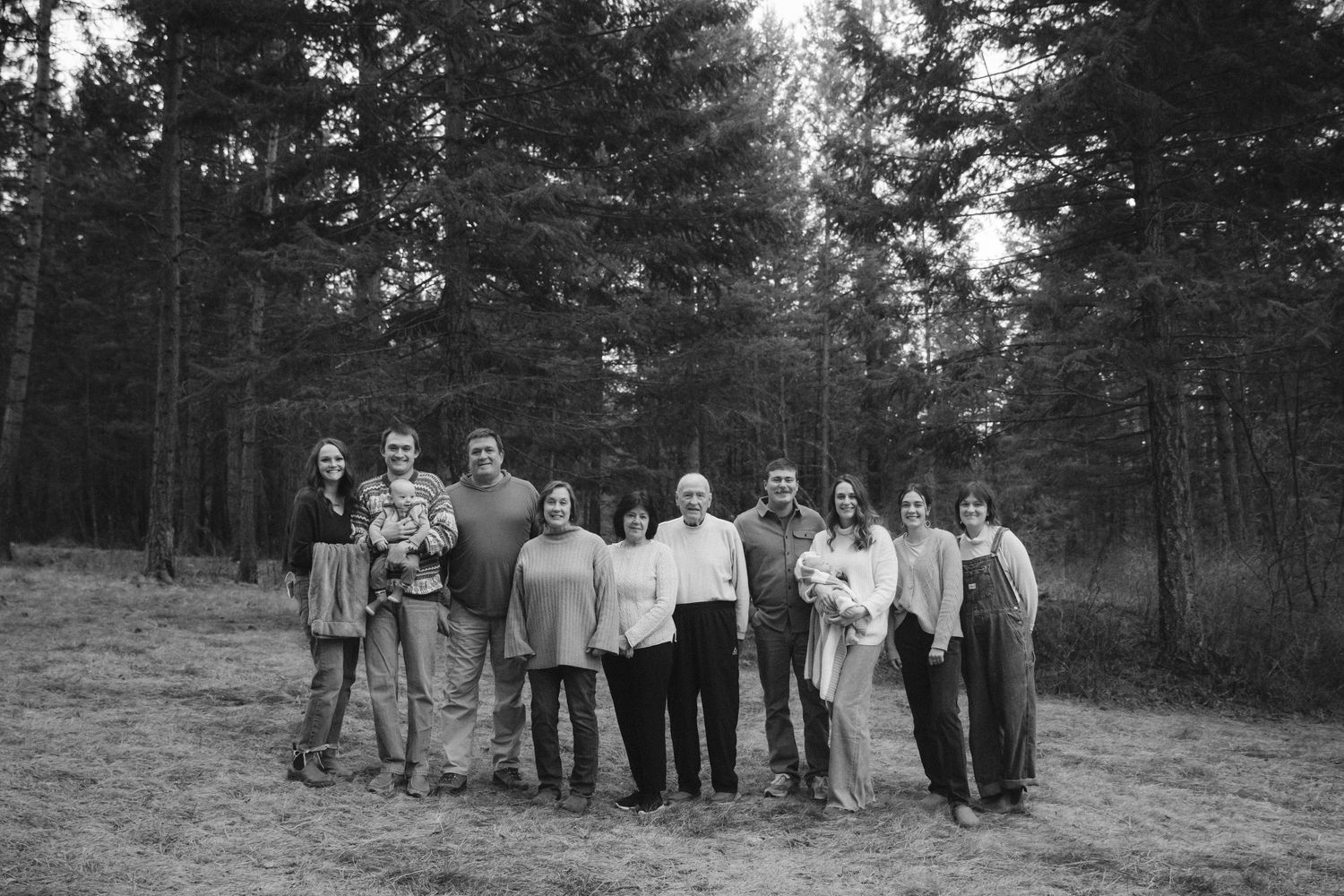 Group photo of people gathered outdoors in wooded forest setting.