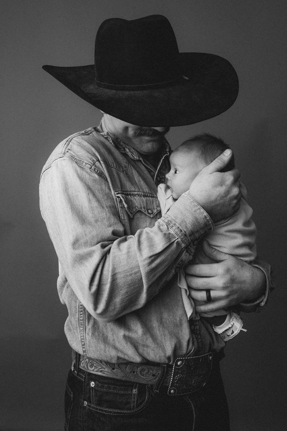 Black and white portrait of person in denim jacket and cowboy hat.