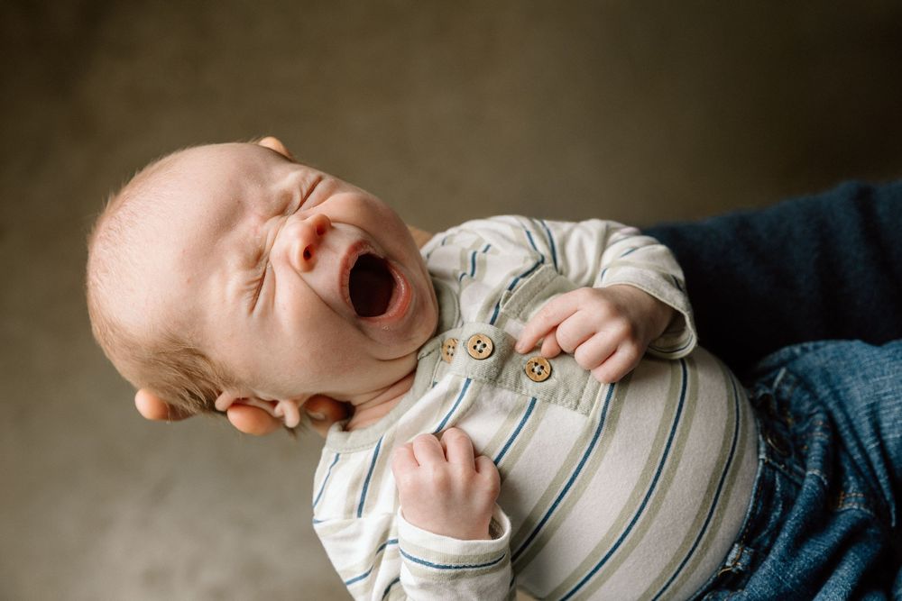 Series of intimate black and white photos showing sleeping newborn in striped outfit.