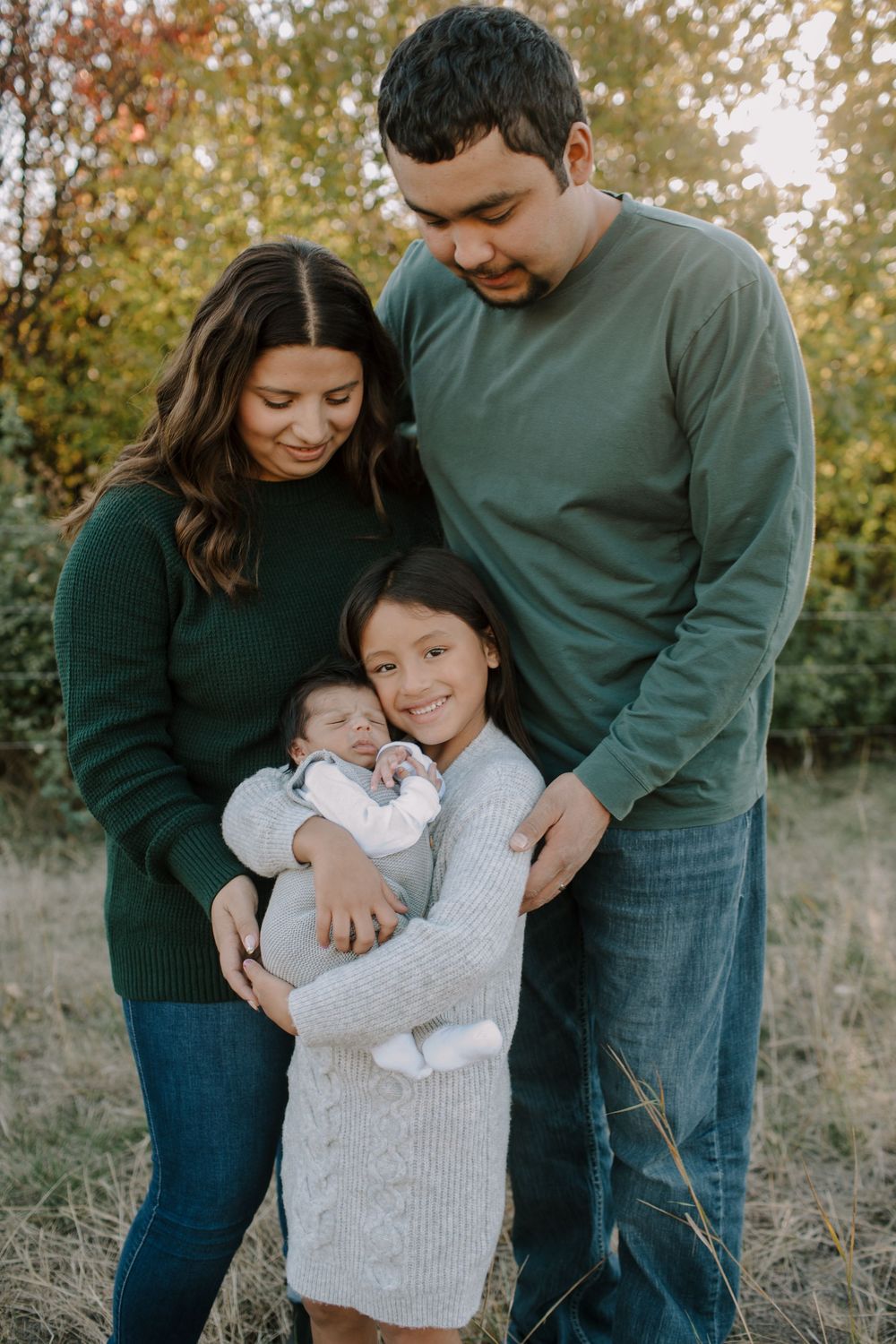 Outdoor family photos showing tender moments with baby in fall scenery.