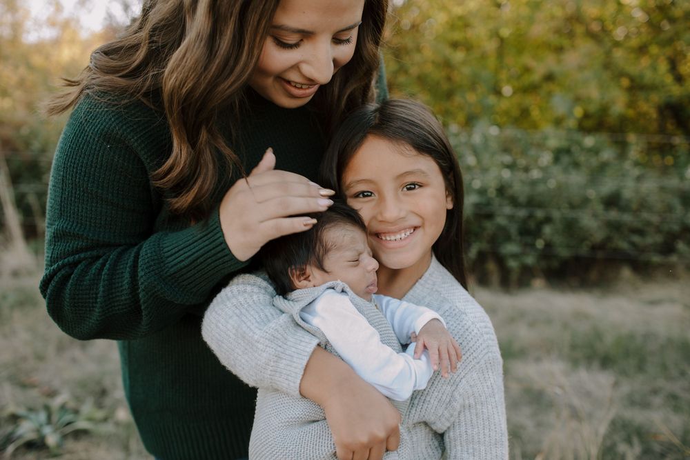 Family portrait series in autumn setting with green sweaters and warm embraces.