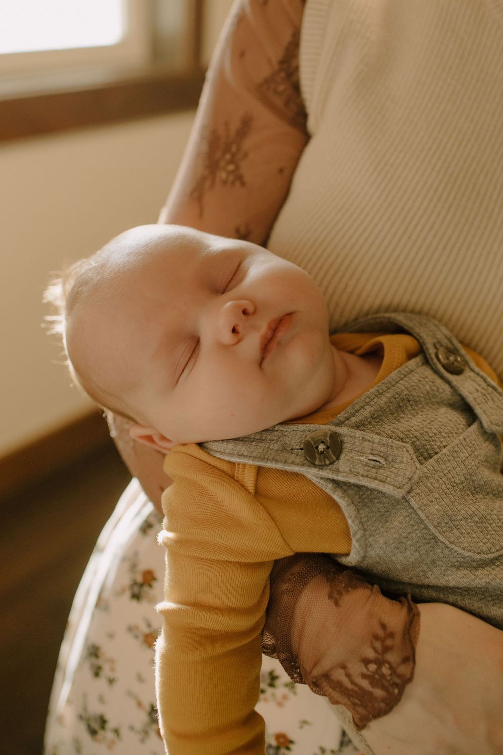 Close-up view of a sleeping baby in a yellow onesie and gray blanket.