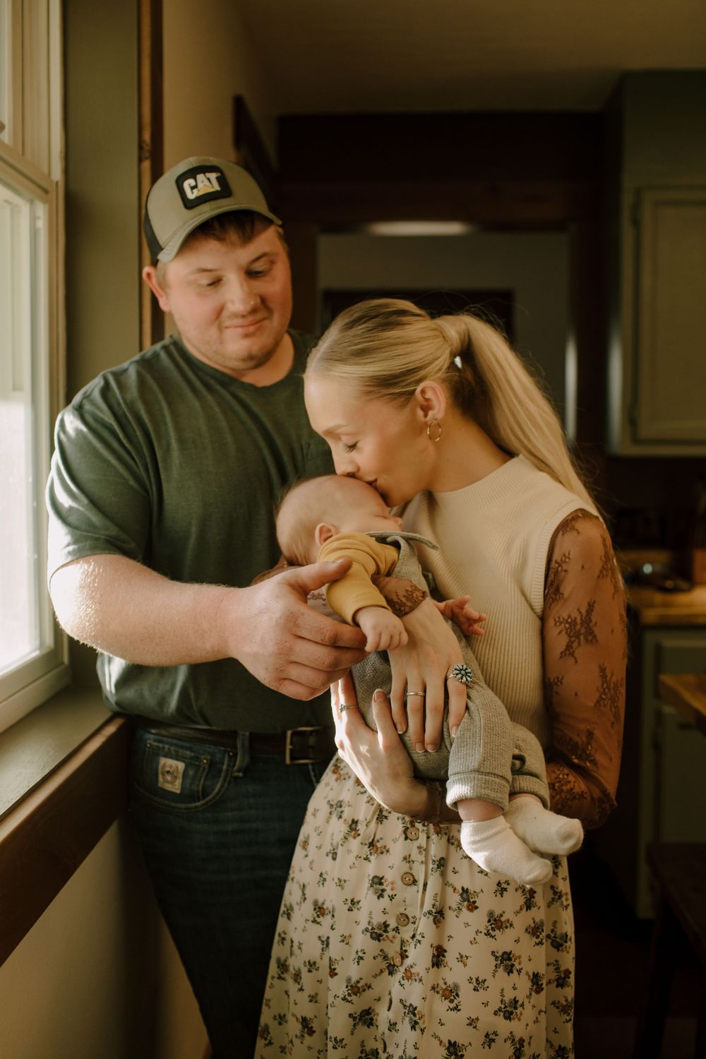 Intimate family moment with parents and baby in a warmly lit room.
