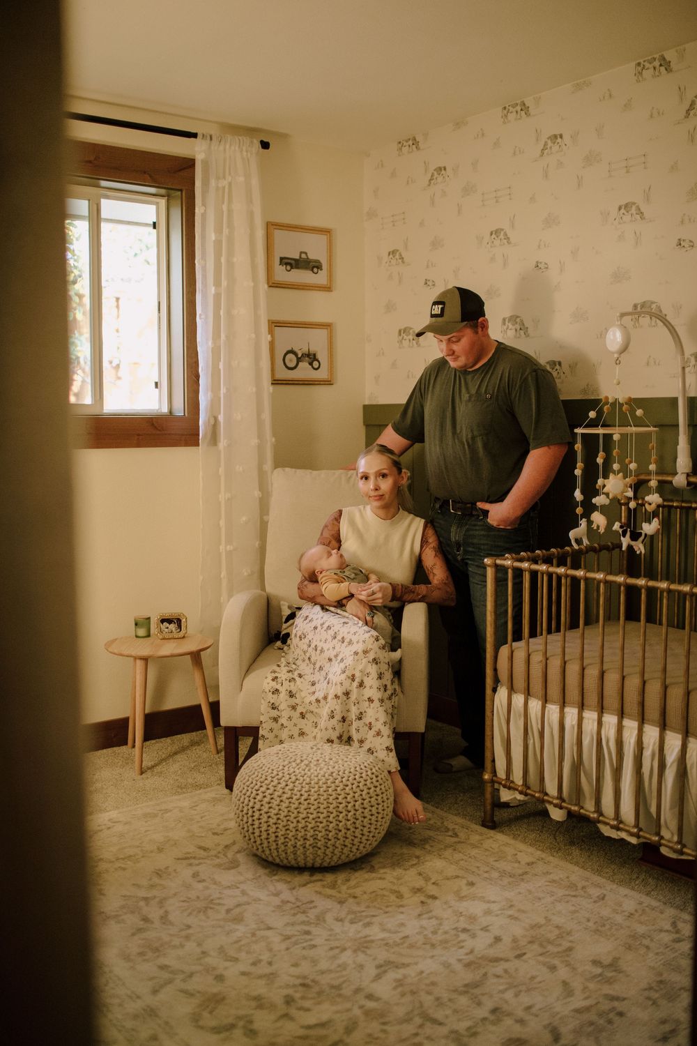 Nursery room interior with floral wallpaper, crib, and knit pouf.