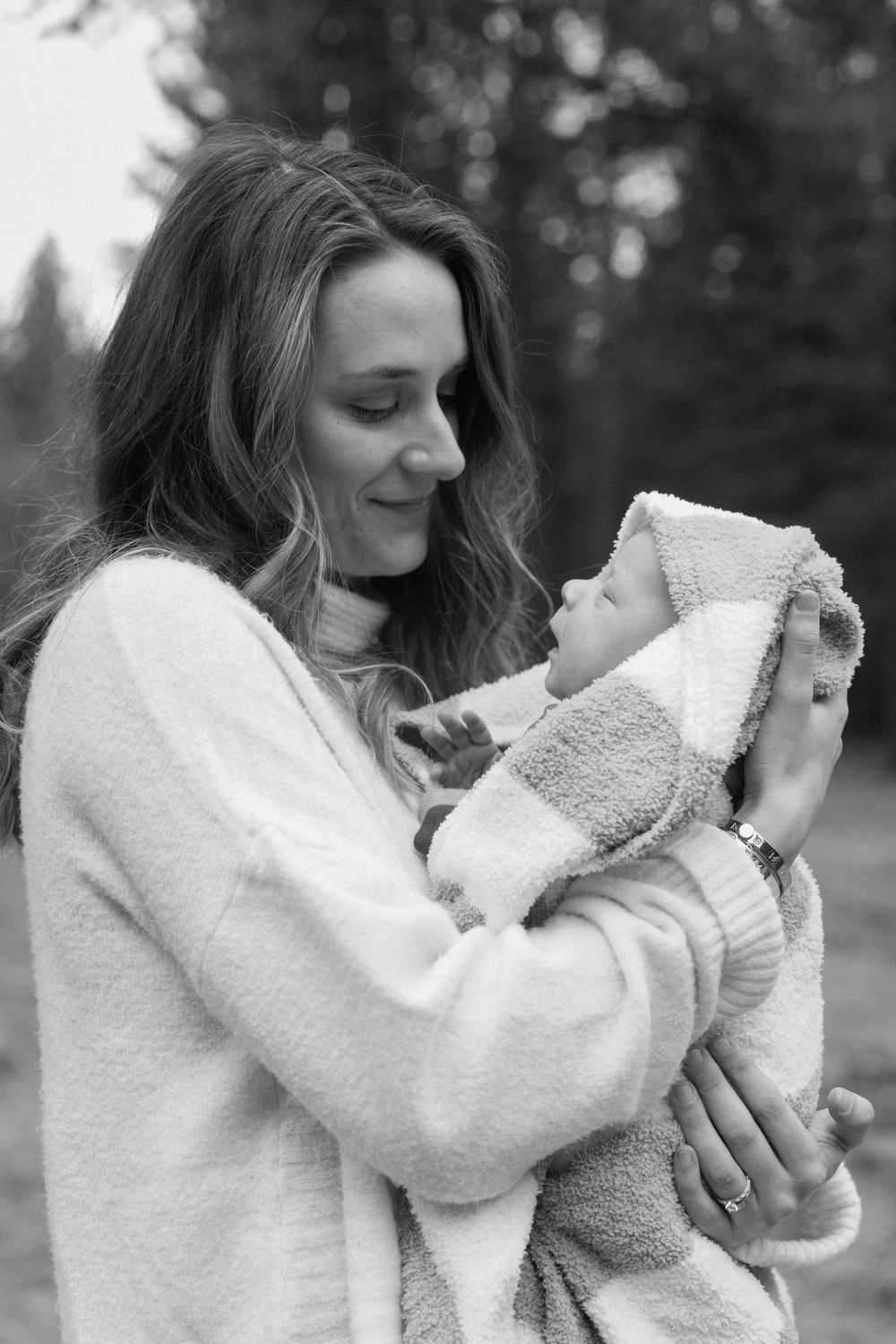 Black and white series showing tender moments with baby wrapped in soft white blanket.