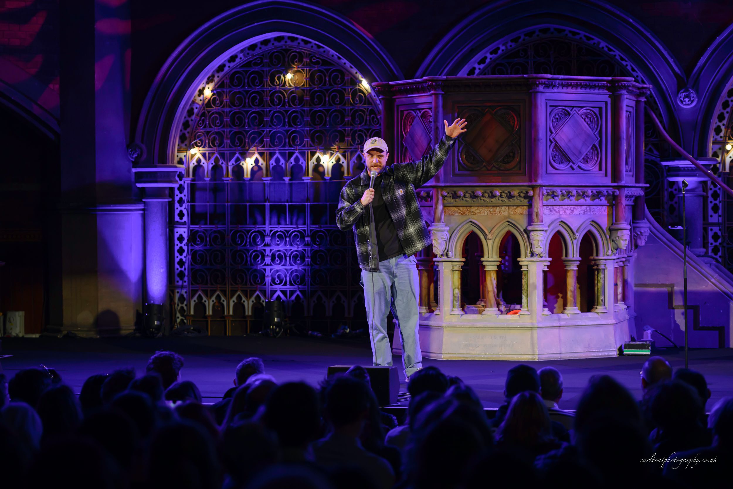 Purple and blue illuminated Gothic cathedral interior with ornate arches and architectural details at night.