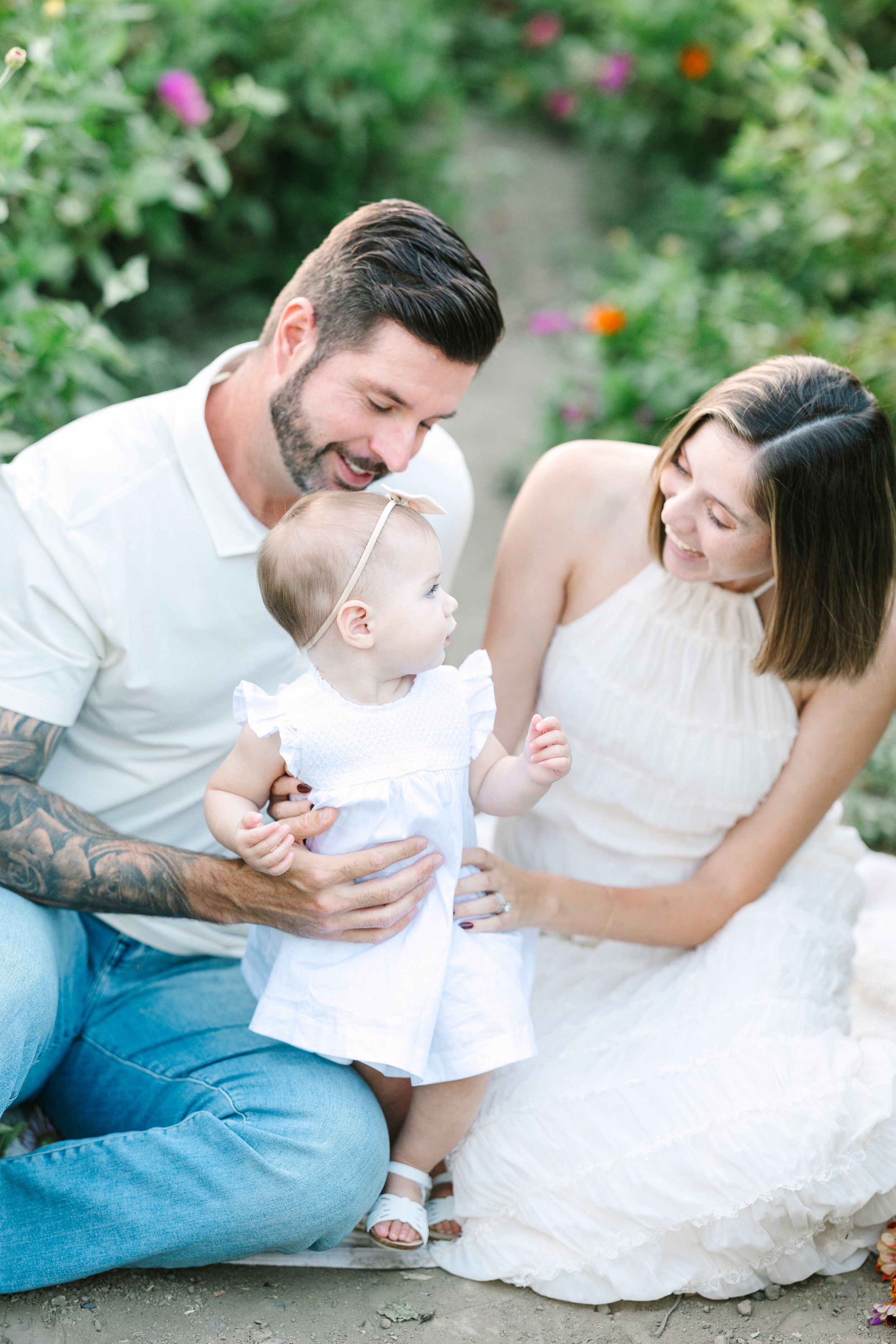 Family moment captured in garden setting with white clothing and natural lighting.