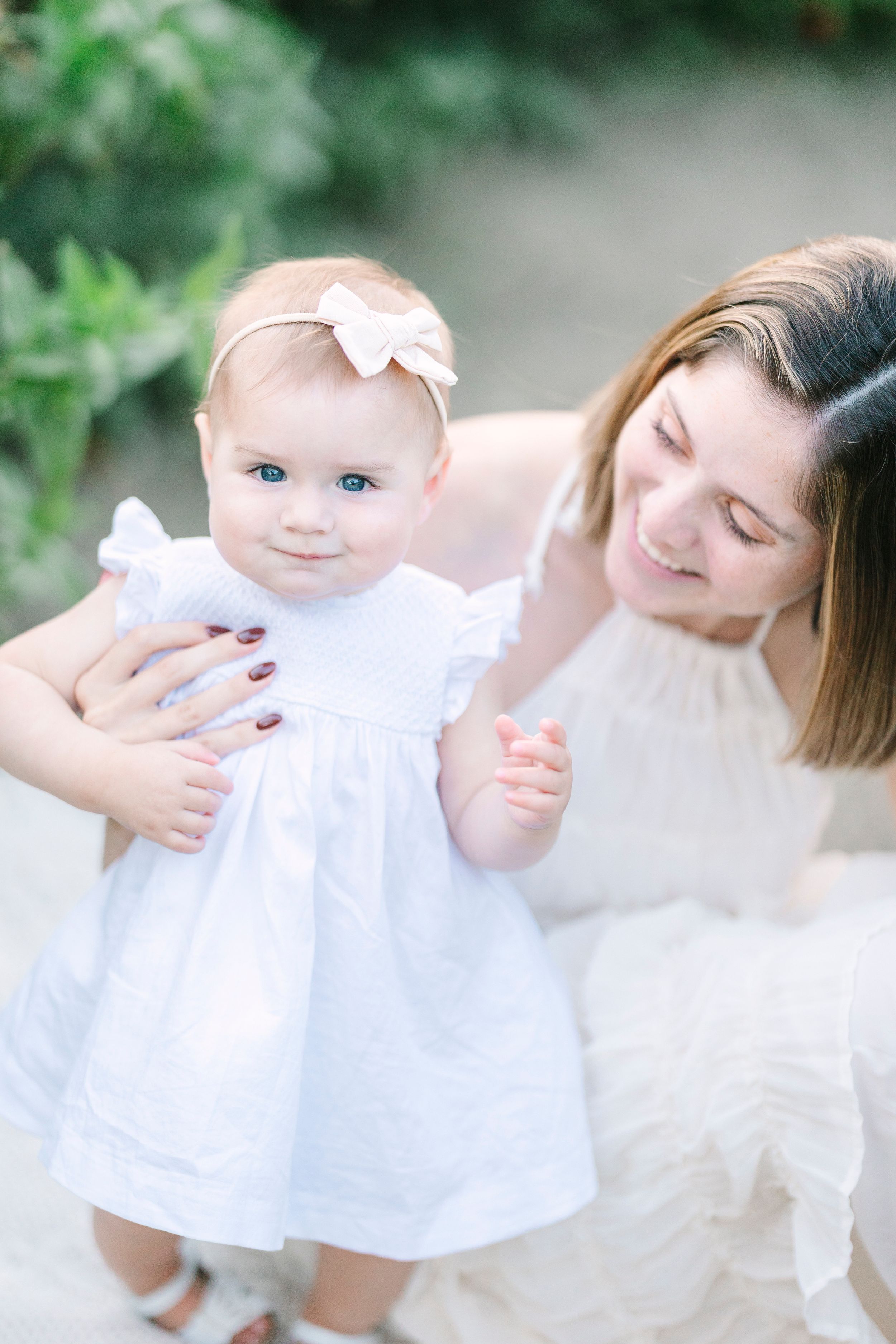 Gentle family moment photographed in garden setting with white clothing and natural light.