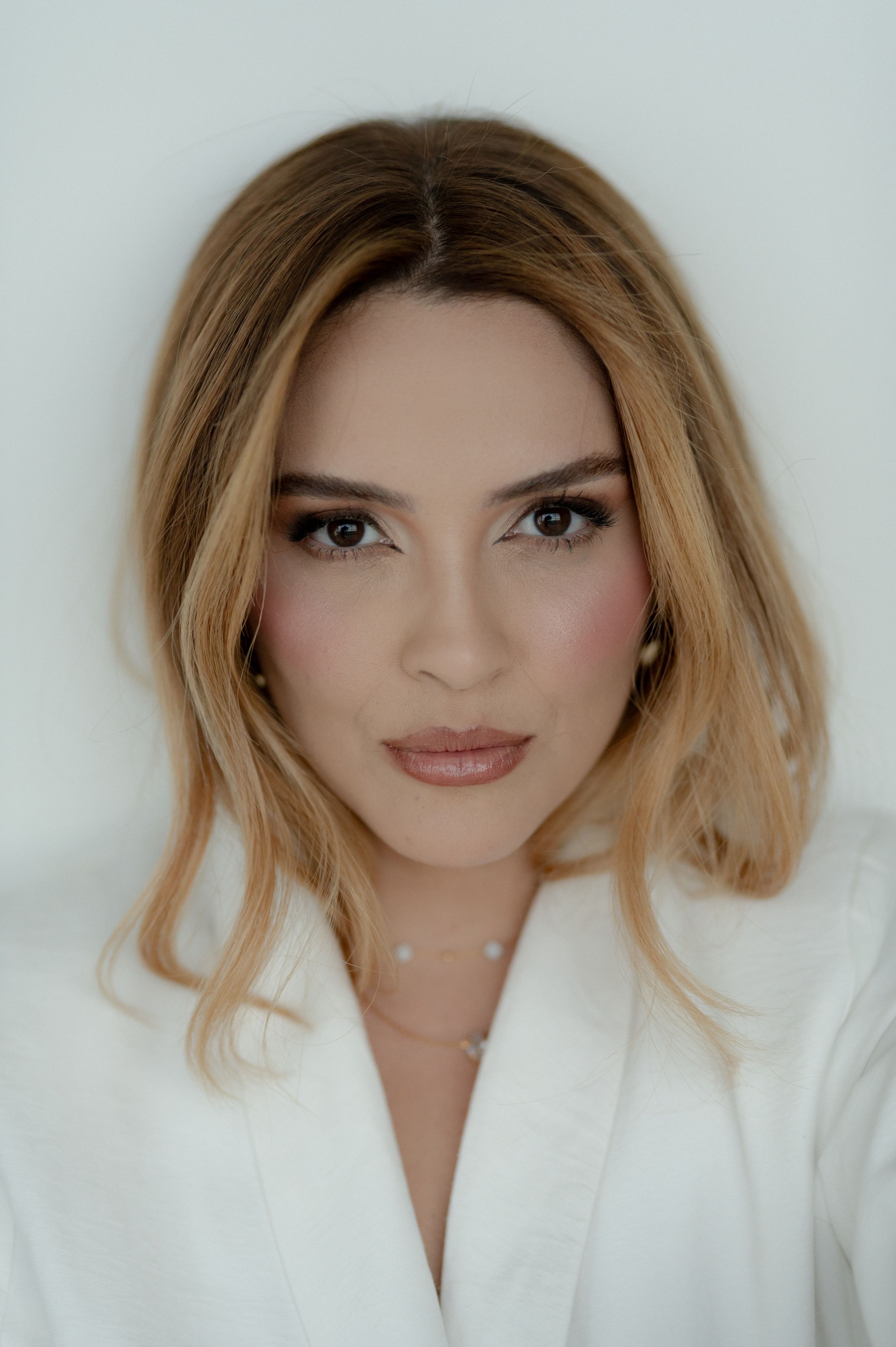 A series of five beauty portraits showing a woman with blonde hair wearing a white top against a light background.