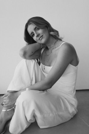 A figure in a flowing white dress poses gracefully against a minimalist gray backdrop in an artistic photo series.