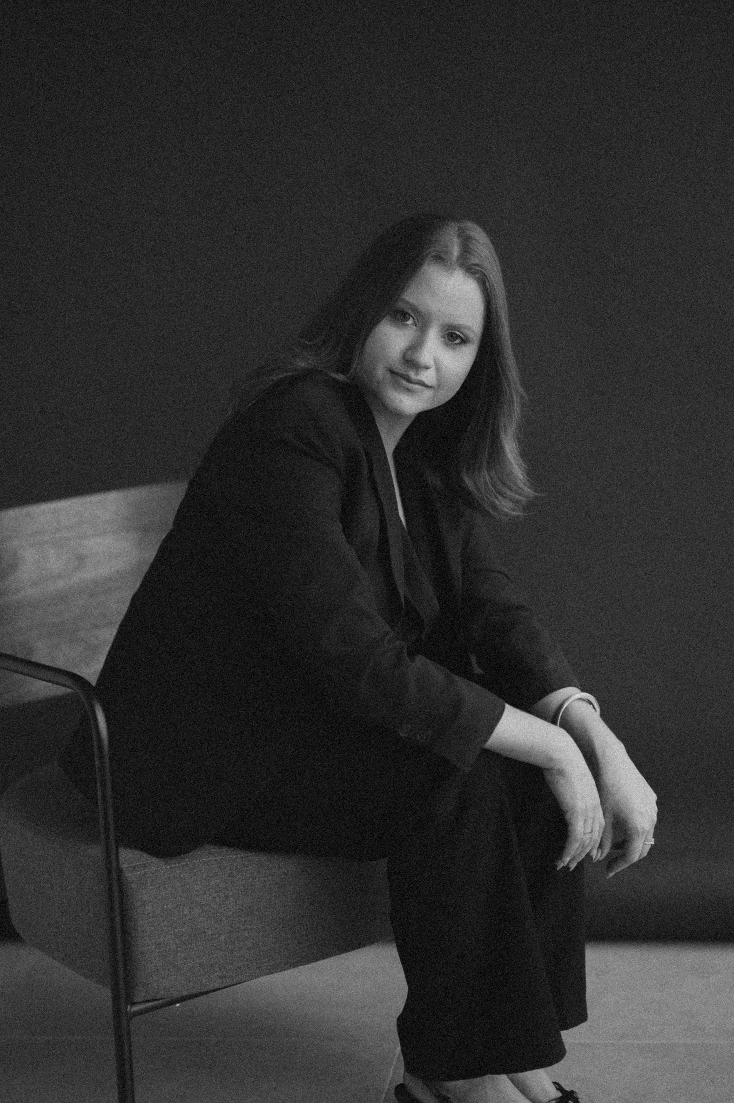 Black and white portrait series showing a figure in dark clothing posed thoughtfully on a chair against a simple backdrop.