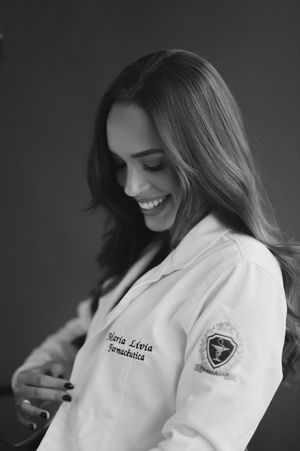 A medical professional in a white coat smiles while looking down in this black and white portrait.