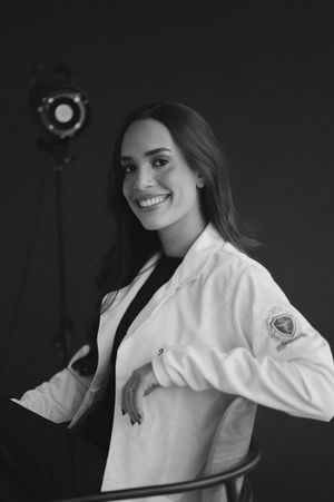 A black and white photo series showing a person in a white medical coat posing playfully against a dark background.