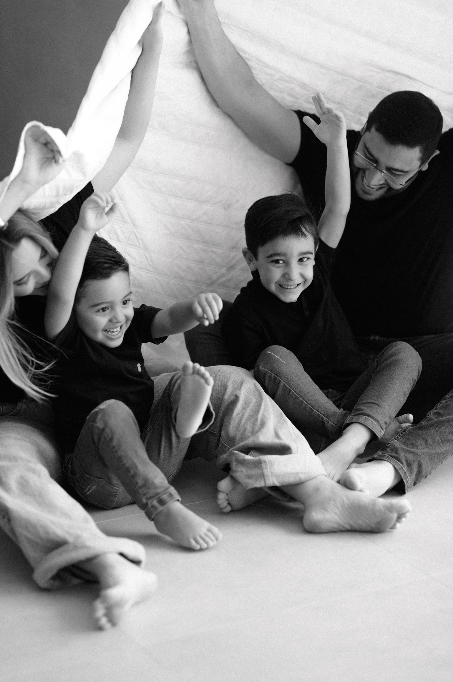 Black and white maternity portrait featuring a woman in a white suit jacket and pants reclining on a floor.