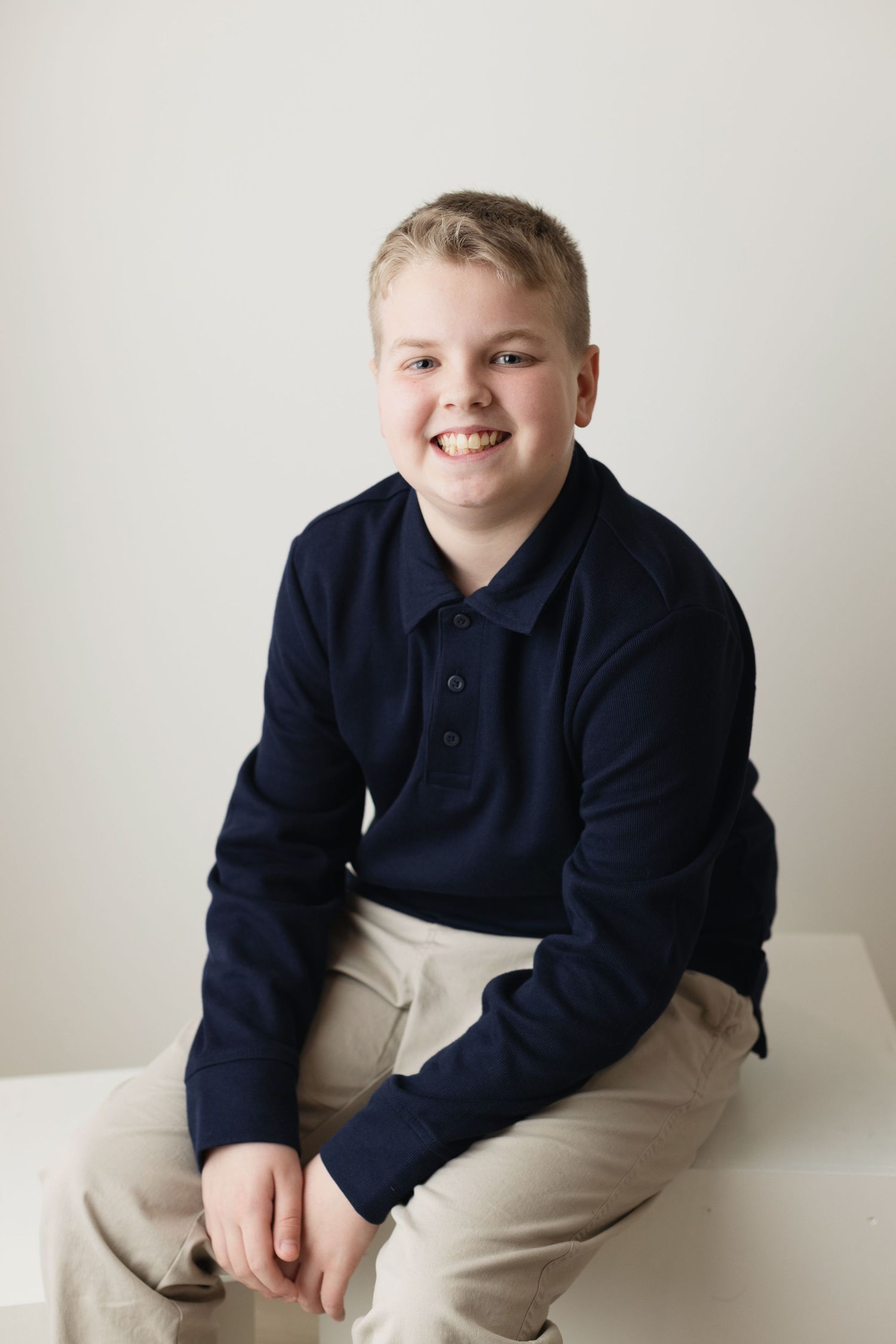 A series of five photos showing a young person in a navy polo shirt and khaki pants posing against a light background.