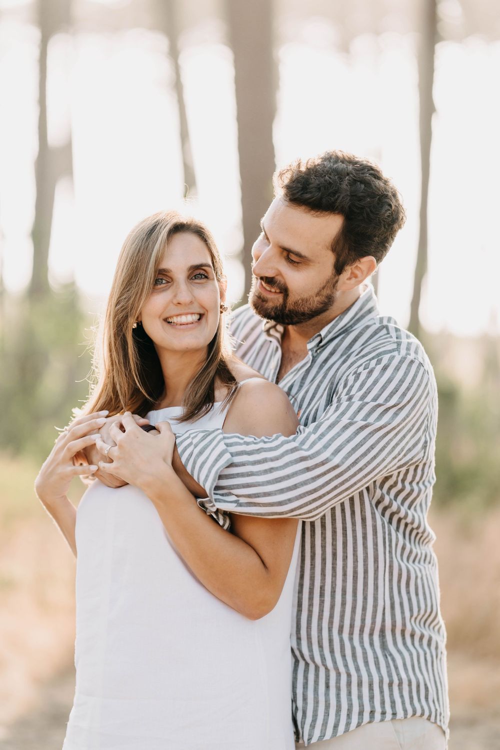 A couple shares intimate moments together outdoors in a series of romantic poses against a soft natural backdrop.